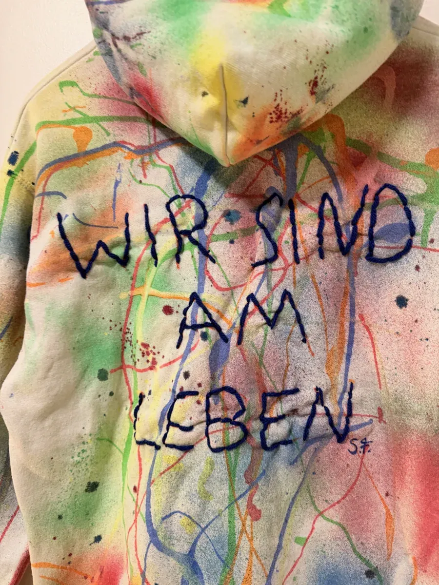 Handbemalter „Wir sind am Leben“-Unikat-Pullover auf dem Bügel