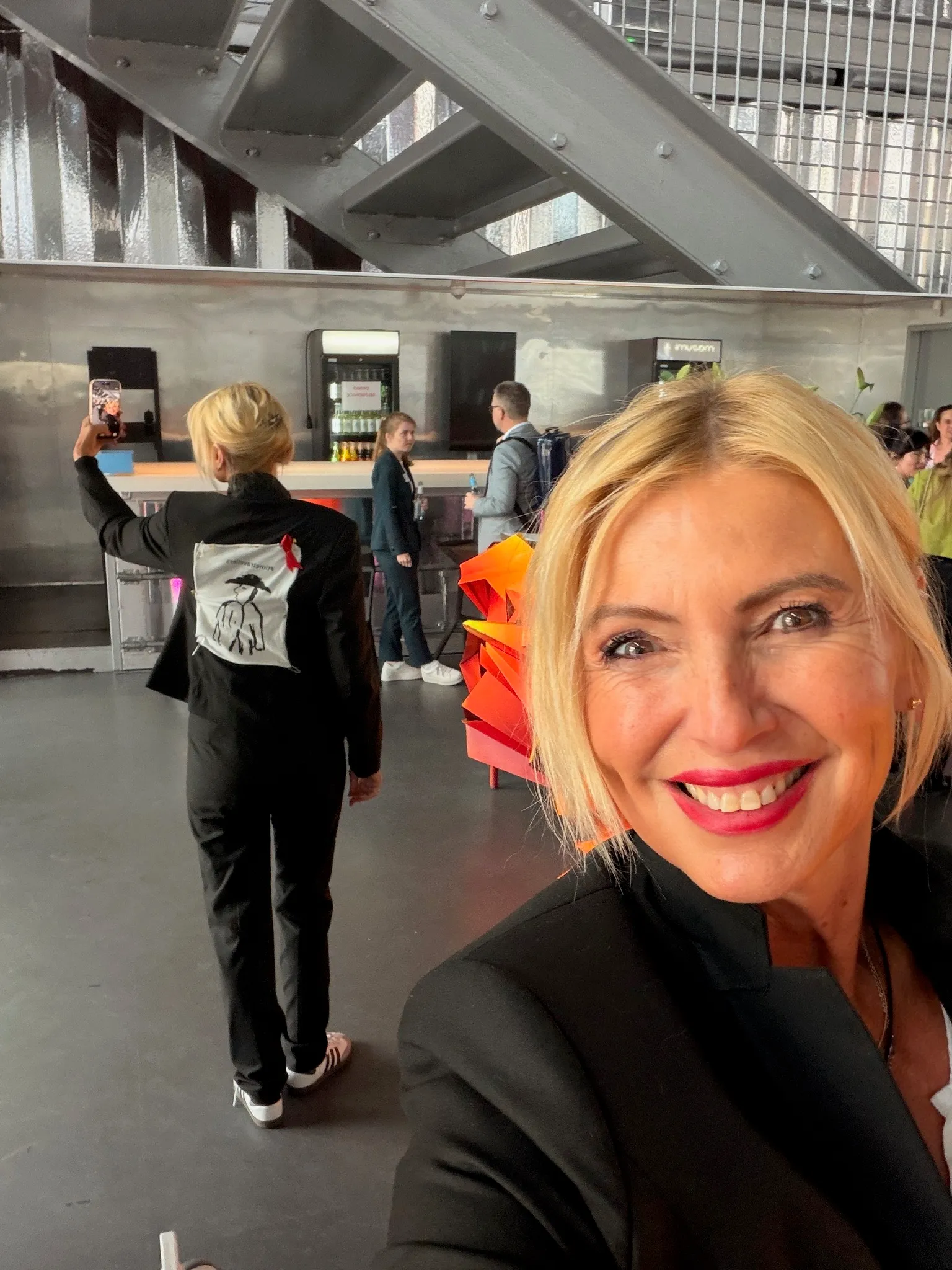 Suzy Forel, Selfie — im Hintergrund ein Blazer mit ihrem Time-Traveller-Männchen